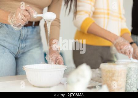 Prozess der Herstellung eines Kunstharzes, abstrakte Kunst. Prozess der Herstellung von Zubehör aus Harz. Master-Klasse auf Harzkunst im Studio. Künstlerfrauen arbeiten mit Stockfoto