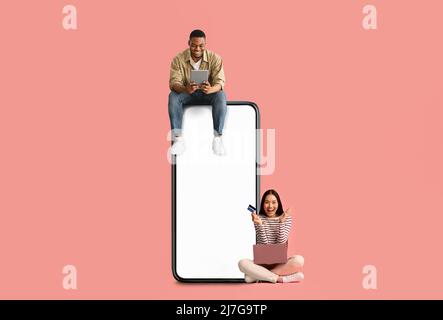 Paar sitzt auf weißem leeren Smartphone-Bildschirm und verwendet Geräte Stockfoto