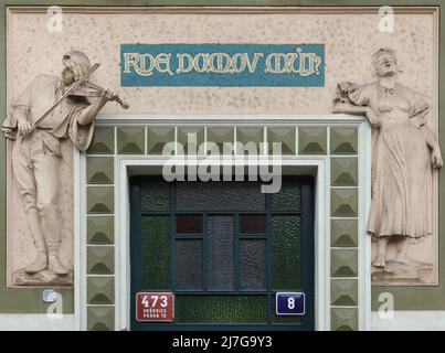 Allegorische Relief der tschechischen Nationalhymne „KDE domov můj?“ („Wo Ist Mein Zuhause?“) Am Einnahmehaus in der Ruská-Straße im Stadtteil Vršovice in Prag, Tschechische Republik. Das vom tschechischen Architekten Osvald Polívka entworfene Jugendstilgebäude wurde zwischen 1905 und 1906 fertiggestellt. Stockfoto