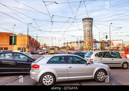 Belebte Straße in Mailand mit vielen Autos, einer Straßenbahn mit Hängekabeln und dem Torre Arcobaleno (Rainbow Tower), Via Carlo Farini e via Giuseppe Ferrari in Stockfoto