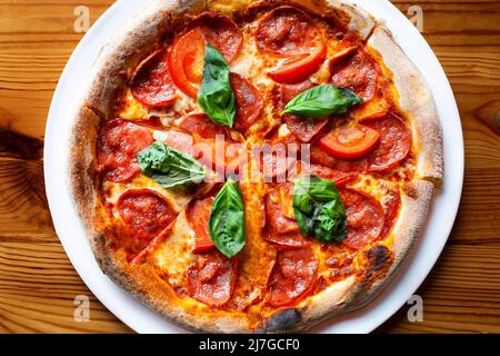 Köstliche Salami-Pizza mit Basilikum und Gewürzen auf der Tischansicht Stockfoto