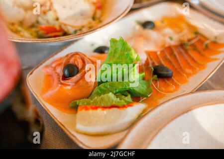 Schale. In Scheiben geschnittener roter Fisch, Salat, Zitrone, Oliven, Microgreens Stockfoto