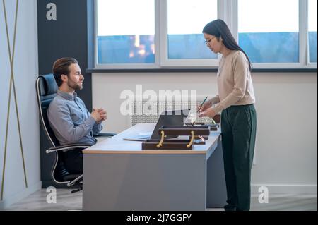 Fokussierte weibliche Assistentin, die dem CEO die Dokumentation vorführt Stockfoto