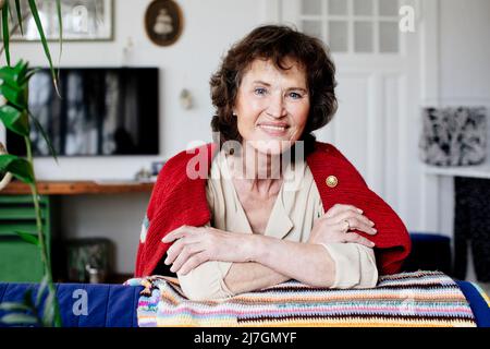 Porträt einer lächelnden älteren Frau, die zu Hause sitzt Stockfoto
