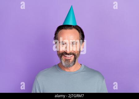 Foto von fröhlich gealterten Mann haben Spaß Jahrestag Veranstaltung Geburtstag Kappe isoliert über violetten Hintergrund Stockfoto