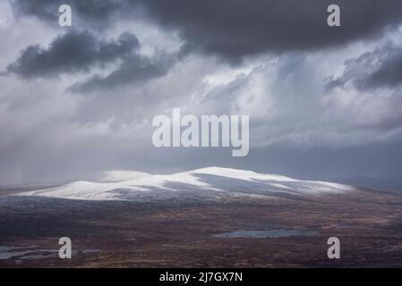 Wunderschöne Winterlandschaft von der Bergspitze in den schottischen Highlands hinunter in Richtung Rannoch Moor während Schneesturm und Spindrift von der Bergspitze hinein Stockfoto