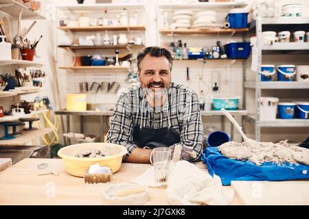 Porträt eines lächelnden, reifen Mannes, der im Kunstunterricht am Tisch sitzt Stockfoto