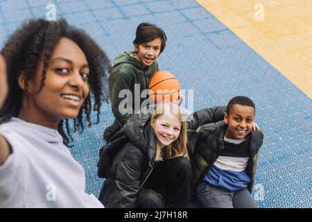Glückliches Mädchen, das Selfie mit multirassischen Freunden auf dem Sportplatz macht Stockfoto