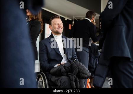 Lächelnder, behinderter Geschäftsmann, der im Rollstuhl sitzt und während des Seminars den männlichen Delegierten anschaut Stockfoto