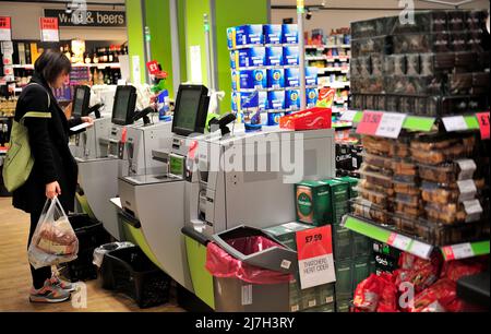 Frau am Supermarkt Selbstbedienungskassen überprüfen Quittung, Großbritannien Stockfoto