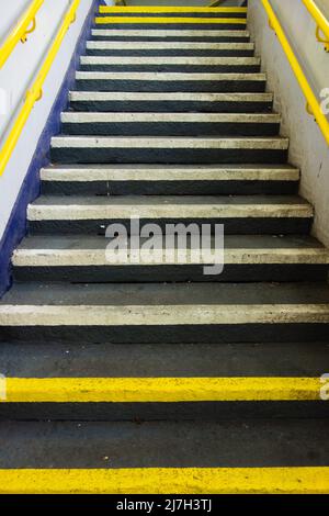 Komplette Zementtreppe mit gelben und weißen Stufen und gelber Handschiene lackiert Stockfoto