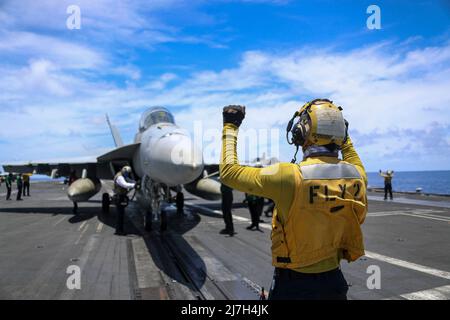 Philippine Sea, Vereinigte Staaten. 08. Mai 2022. Ein Seemann der US-Marine leitet ein F/A-18E Super Hornet Kampfflugzeug, das den Black Aces of Strike Fighter Squadron 41 zugewiesen wurde, während einer Routinepatrouille am 8. Mai 2022 im philippinischen Meer vom Flugdeck des Flugzeugträgers USS Abraham Lincoln in die Startposition. Kredit: MC3 Javier Reyes/U.S. Navy Photo/Alamy Live News Stockfoto