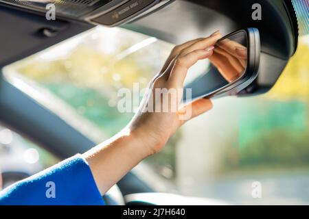 Nahaufnahme der Hand der Frau, die den Rückspiegel im Auto anpasst. Stockfoto