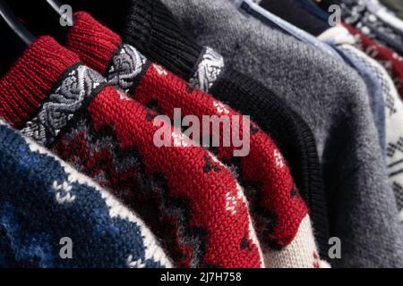 Handgefertigte skandinavische Wolljacke für Damen, Pullover im norwegischen Stil in allen möglichen Farben und Mustern, in einem Marktstand unter freiem Himmel Stockfoto