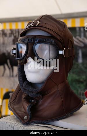 Winddichter, mit Fell gefütterter Lederhut mit passender Sonnenbrille auf einem Styropor-Kopf in einem Marktstand. Gesichtsschutz im Schnee oder auf dem Motorrad Stockfoto