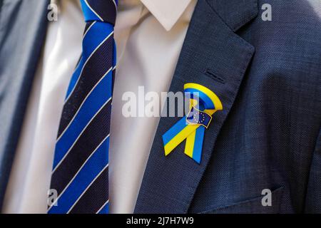 Bukarest, Rumänien - 9. Mai 2022: Details zur geringen Schärfentiefe (selektiver Fokus) mit der ukrainischen Flagge und dem Logo der Europäischen Union auf dem Anzug Stockfoto