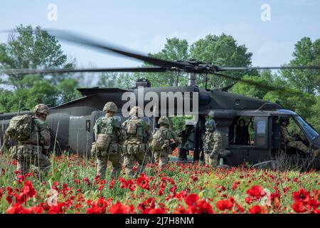 Krivolak, Norden, Mazedonien. 08.. Mai 2022. Britische Soldaten, die dem Kampfteam der Luftangriffsbrigade 16. zugewiesen wurden, laden in einen Hubschrauber der US Army 1. Air Cavalry Brigade UH-60 Blackhawk in einem Feld aus rotem Mohn für eine Flugangriffstrainingsmission während der Übung Swift Response, im Krivolak Military Training Center, 8. Mai 2022 in Krivolak, Nordmakedonien. Kredit: Sgt. Jason Greaves/U.S. Army/Alamy Live News Stockfoto