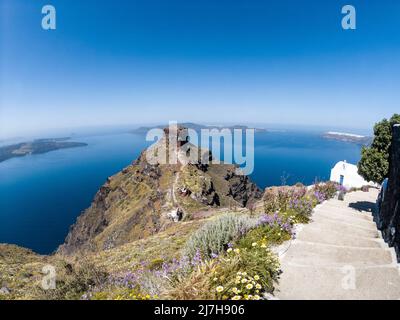 Wunderschöne Aussicht auf den Felshügel von Skaros, auf der Insel Santorini, Griechenland, und Meerblick auf den vulkanischen Teil von Santorini und die legendäre Caldera. Stockfoto