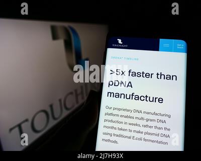 Person hält Handy mit Webseite der Biotechnologie-Firma Touchlight Genetics Ltd. Auf dem Bildschirm mit Logo. Konzentrieren Sie sich auf die Mitte des Telefondisplays. Stockfoto