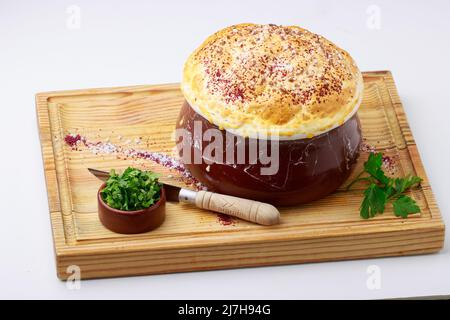 Putuk / Piti - traditionelle armenische Kichererbsen und Lammeintopf in einem Tontopf mit Fladenbrot bedeckt serviert. Stockfoto