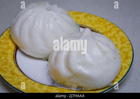 Zwei weiße chinesische Dampfbrötchen (Baozi) auf einem Teller Stockfoto