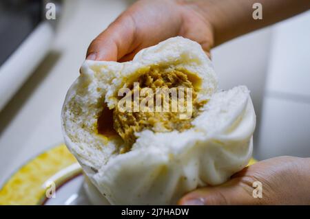 Halbgeöffnete chinesische Dampfbrötchen (cha siu bao), die die Füllung des Fleisch-Veggie im Inneren zeigen. Stockfoto