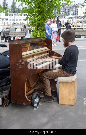 Ein männlicher Straßenmusiker, der in Bowness auf Windermere im Lake District, England, Großbritannien, Klavier spielt Stockfoto