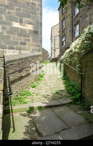 Steinhütten und gewundene gepflasterte Wege über der West-yorkshire-Stadt Holmfirth. Stockfoto