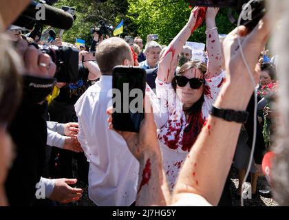 Warschau, Polen. 09.. Mai 2022. Irina Zamlyan verwendet gefälschtes Blut, während sie in der Nähe des russischen Botschafters Sergey Andreev auftritt (nicht auf dem Foto zu sehen). Am 77.. Jahrestag des Sieges der Roten Armee über Nazi-Deutschland traten ukrainische Aktivisten auf dem sowjetischen Soldatenfriedhof in Warschau auf, als sie gegen die russische Invasion in der Ukraine protestierten. Aktivisten verboten der russischen Delegation unter der Leitung von Sergej Andreev, dem Botschafter der Russischen Föderation in Polen, den Eintritt in den Friedhof. Während dieses Versuchs wurden Diplomaten von ukrainischen Aktivisten mit gefälschtem Blut übergossen. Stockfoto