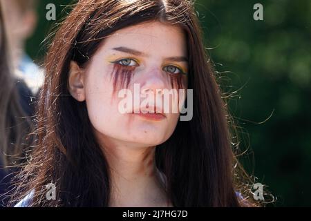 Warschau, Polen. 09.. Mai 2022. Frau mit gemaltem Gesicht nimmt am Tag des Sieges an einem Protest auf dem sowjetischen Soldatenfriedhof in Warschau Teil. Am 77.. Jahrestag des Sieges der Roten Armee über Nazi-Deutschland traten ukrainische Aktivisten auf dem sowjetischen Soldatenfriedhof in Warschau auf, als sie gegen die russische Invasion in der Ukraine protestierten. Aktivisten verboten der russischen Delegation unter der Leitung von Sergej Andreev, dem Botschafter der Russischen Föderation in Polen, den Eintritt in den Friedhof. Während dieses Versuchs wurden Diplomaten von ukrainischen Aktivisten mit gefälschtem Blut übergossen. Stockfoto