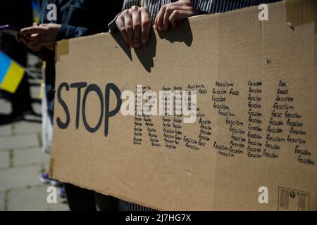 Warschau, Polen. 09.. Mai 2022. Frau hält ein Plakat während der Demonstration auf dem sowjetischen Soldatenfriedhof in Warschau am Tag des Sieges. Am 77.. Jahrestag des Sieges der Roten Armee über Nazi-Deutschland traten ukrainische Aktivisten auf dem sowjetischen Soldatenfriedhof in Warschau auf, als sie gegen die russische Invasion in der Ukraine protestierten. Aktivisten verboten der russischen Delegation unter der Leitung von Sergej Andreev, dem Botschafter der Russischen Föderation in Polen, den Eintritt in den Friedhof. Während dieses Versuchs wurden Diplomaten von ukrainischen Aktivisten mit gefälschtem Blut übergossen. Stockfoto