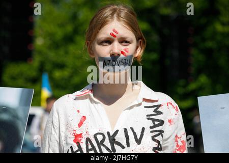 Warschau, Polen. 09.. Mai 2022. Ein Protestler mit mit Klebeband versiegelten Lippen nimmt an dem Protest Teil. Am 77.. Jahrestag des Sieges der Roten Armee über Nazi-Deutschland traten ukrainische Aktivisten auf dem sowjetischen Soldatenfriedhof in Warschau auf, als sie gegen die russische Invasion in der Ukraine protestierten. Aktivisten verboten der russischen Delegation unter der Leitung von Sergej Andreev, dem Botschafter der Russischen Föderation in Polen, den Eintritt in den Friedhof. Während dieses Versuchs wurden Diplomaten von ukrainischen Aktivisten mit gefälschtem Blut übergossen. Kredit: SOPA Images Limited/Alamy Live Nachrichten Stockfoto