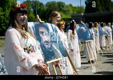 Warschau, Polen. 09.. Mai 2022. Frauen in blutig-stilvollen weißen Kleidern, die während der Aufführung auf dem sowjetischen Soldatenfriedhof in Warschau am Tag des Sieges gesehen wurden. Am 77.. Jahrestag des Sieges der Roten Armee über Nazi-Deutschland traten ukrainische Aktivisten auf dem sowjetischen Soldatenfriedhof in Warschau auf, als sie gegen die russische Invasion in der Ukraine protestierten. Aktivisten verboten der russischen Delegation unter der Leitung von Sergej Andreev, dem Botschafter der Russischen Föderation in Polen, den Eintritt in den Friedhof. Während dieses Versuchs wurden Diplomaten von ukrainischen Aktivisten mit gefälschtem Blut übergossen. Stockfoto