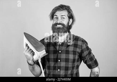 Nur einen Moment. Glückliche Verkäuferin im karierten Hemd. Bärtiger Mann. Neue Technologie. Reifer Hipster mit Bart verwenden dampfendes Eisen. Brutaler Kaukasier Stockfoto