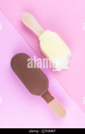 Eis auf Stick Vanille und Schokolade. Zwei Eisdielen auf einem Holzstock Draufsicht flach Lay Sommer Konzept auf rosa Hintergrund Stockfoto