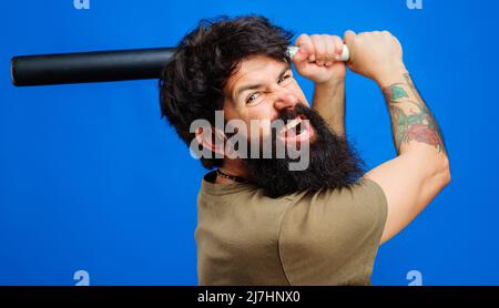 Wütender bärtiger Mann schwingt Baseballschläger. Sportausrüstung. Konzept von Gewalt, Angriff und Aggression. Stockfoto