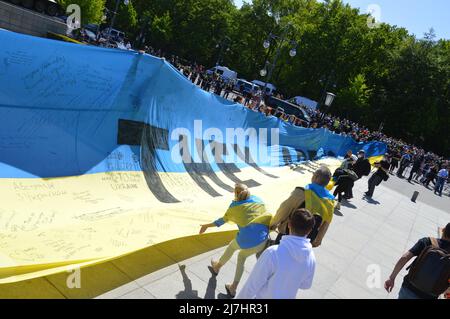 Am 8. Mai 2022 halten Menschen eine große ukrainische Flagge am sowjetischen Kriegsdenkmal im Tiergarten in Berlin. Stockfoto