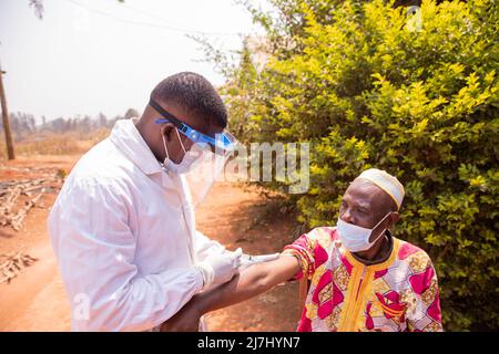 Älterer afrikanischer Mann, der während der Pandemie-Ära Covid-19 im Freien geimpft wurde. Stockfoto