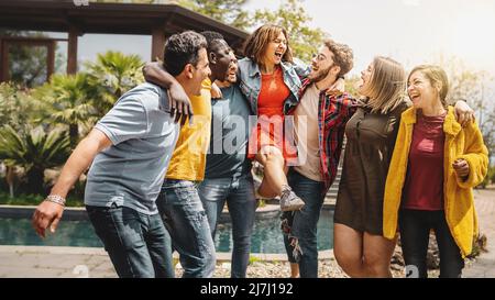 Mehrere Generationen von Freunden, die Spaß haben, zusammen zu spielen und die Arme auf den Schultern zu umarmen - bunte multikulturelle Gemeinschaft von sorglosen glücklichen Menschen o Stockfoto