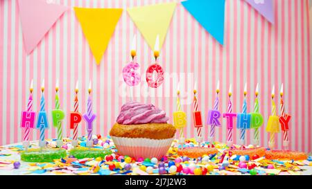 Alles Gute zum Geburtstag. Auf einem rosa Hintergrund ein Happy Birthday Gruß für ein Kind. Cupcakes mit rosa Creme und brennender Kerze. Speicherplatz kopieren. Stockfoto