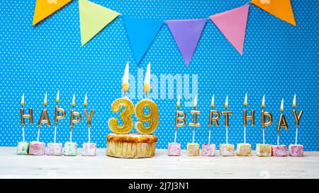Alles gute zum Geburtstag aus Kerzenbuchstaben auf blauem Hintergrund mit weißem Tupfen-Kopierraum. Alles gute zum Geburtstag Cupcake mit brennender goldener Kerze Stockfoto