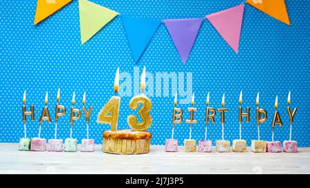 Alles gute zum Geburtstag aus Kerzenbuchstaben auf blauem Hintergrund mit weißem Tupfen-Kopierraum. Alles gute zum Geburtstag Cupcake mit brennender goldener Kerze Stockfoto