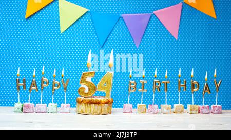 Alles gute zum Geburtstag aus Kerzenbuchstaben auf blauem Hintergrund mit weißem Tupfen-Kopierraum. Alles gute zum Geburtstag Cupcake mit brennender goldener Kerze Stockfoto