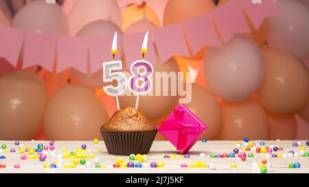 Ballondekorationen und eine Geburtstagskerze mit einer Nummer in einem Kuchen. Alles gute zum Geburtstag Grüße in rosa Farben für ein Mädchen, Platz kopieren. Muffin Stockfoto