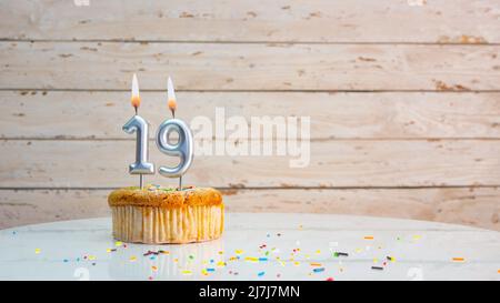 Alles gute zum Geburtstag silberne Ziffern auf weißen Brettern Hintergrund kopieren Raum. Schöne Geburtstagskarte mit einem Cupcake mit brennender Kerze Stockfoto