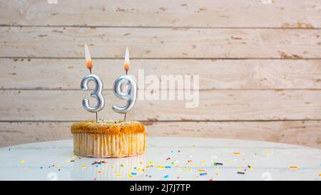 Alles gute zum Geburtstag silberne Ziffern auf weißen Brettern Hintergrund kopieren Raum. Schöne Geburtstagskarte mit einem Cupcake mit brennender Kerze Stockfoto