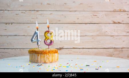 Alles gute zum Geburtstag silberne Ziffern auf weißen Brettern Hintergrund kopieren Raum. Schöne Geburtstagskarte mit einem Cupcake mit brennender Kerze Stockfoto