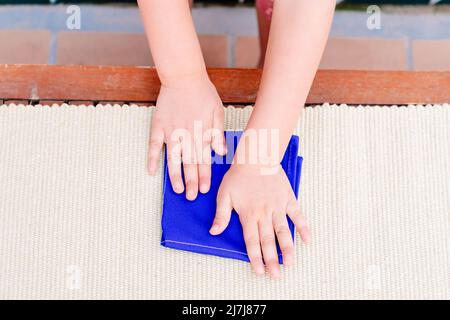 Hände eines Mädchens in einer montessori-Schule im Bereich des täglichen Lebens, Falten einer Serviette. Stockfoto