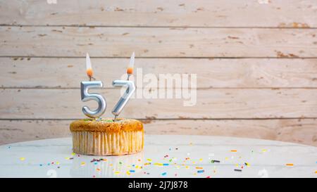 Alles gute zum Geburtstag silberne Ziffern auf weißen Brettern Hintergrund kopieren Raum. Schöne Geburtstagskarte mit einem Cupcake mit brennender Kerze Stockfoto