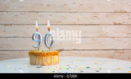 Alles gute zum Geburtstag silberne Ziffern auf weißen Brettern Hintergrund kopieren Raum. Schöne Geburtstagskarte mit einem Cupcake mit brennender Kerze Stockfoto